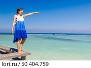 Beautiful woman on a beautiful tropical beach pointing to somewhere . Стоковое фото, агентство Ingram Publishing / Фотобанк Лори