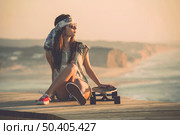 Beautiful young fashion skater girl looking at the sunset. Стоковое фото, агентство Ingram Publishing / Фотобанк Лори