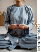 front view woman meditating with beads. Стоковое фото, агентство Ingram Publishing / Фотобанк Лори