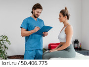 male osteopathic therapist with female patient signing clipboard clinic. Стоковое фото, агентство Ingram Publishing / Фотобанк Лори