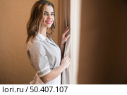 portrait young smiling maid fixes curtain hotel room. Стоковое фото, агентство Ingram Publishing / Фотобанк Лори