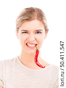 Beautiful girl making a silly face biting a red chilli pepper, isolated over a white background. Стоковое фото, агентство Ingram Publishing / Фотобанк Лори