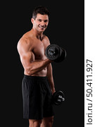 Portrait of a muscular man lifting weights against a dark background. Стоковое фото, агентство Ingram Publishing / Фотобанк Лори