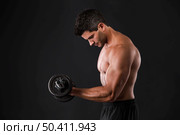 Portrait of a muscular man lifting weights against a dark background. Стоковое фото, агентство Ingram Publishing / Фотобанк Лори