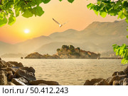 Castle Sveti Stefan on an island in the sea at sunset. Sveti Stefan on horizon. Стоковое фото, агентство Ingram Publishing / Фотобанк Лори
