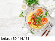 Omelette or omelet, fresh arugula and tomato salad and toasts with butter and salted salmon, top view. Стоковое фото, агентство Ingram Publishing / Фотобанк Лори