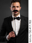 Handsome young man holding a fake mustache. Стоковое фото, агентство Ingram Publishing / Фотобанк Лори
