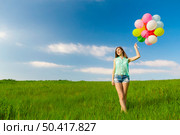 Young beautiful woman with colorful balloons on a green meadow. Стоковое фото, агентство Ingram Publishing / Фотобанк Лори
