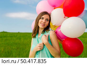 Young beautiful woman with colorful balloons on a green meadow. Стоковое фото, агентство Ingram Publishing / Фотобанк Лори