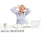 Stressed elderly woman working in the office with a laptop. Стоковое фото, агентство Ingram Publishing / Фотобанк Лори
