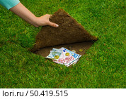 Finances concept, hands hiding money under the grass. Стоковое фото, агентство Ingram Publishing / Фотобанк Лори