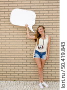Beautiful and young teenager holding a thought balloon, in front of a brick wall. Стоковое фото, агентство Ingram Publishing / Фотобанк Лори