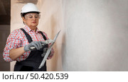female construction worker with helmet smoothing wall. Стоковое фото, агентство Ingram Publishing / Фотобанк Лори