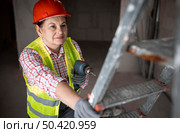 high angle female construction worker with electric drill. Стоковое фото, агентство Ingram Publishing / Фотобанк Лори