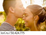 Portrait of a happy young couple in love and giving a kiss. Стоковое фото, агентство Ingram Publishing / Фотобанк Лори
