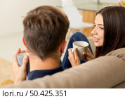 Young couple on the sofa drinking coffee. Стоковое фото, агентство Ingram Publishing / Фотобанк Лори