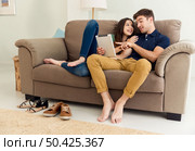 Young couple sitting on the sofa and watching something on a tablet. Стоковое фото, агентство Ingram Publishing / Фотобанк Лори