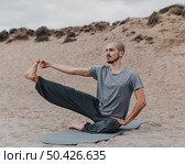 man stretching his leg while doing yoga outdoors. Стоковое фото, агентство Ingram Publishing / Фотобанк Лори