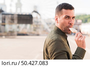 stubble young man eating popsicle icecream amusement park. Стоковое фото, агентство Ingram Publishing / Фотобанк Лори