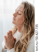 side view woman praying with eyes closed. Стоковое фото, агентство Ingram Publishing / Фотобанк Лори