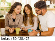 Friends studying together and watching something on the phone. Стоковое фото, агентство Ingram Publishing / Фотобанк Лори