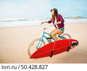 Surfer young woman riding her bicycle on the beach. Стоковое фото, агентство Ingram Publishing / Фотобанк Лори