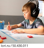 child wearing headphones attending virtual classes 2. Стоковое фото, агентство Ingram Publishing / Фотобанк Лори