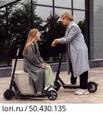couple conversing while being outdoors with electric scooters. Стоковое фото, агентство Ingram Publishing / Фотобанк Лори