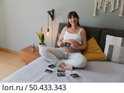 Pregnant woman holding the picture of the ultrasound on her belly in bed at home. Prenatal health care concept. Стоковое фото, агентство Ingram Publishing / Фотобанк Лори