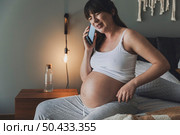 Painful pregnant young woman at home calling medical assistance on phone . Стоковое фото, агентство Ingram Publishing / Фотобанк Лори