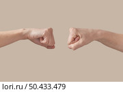 Two hands male and woman fist bumping symbol of friendship, good job, great work isolated on beige background. Brotherhood awesome fists bump as agreement.. Two hands male and female hands fist bump on beige. Стоковое фото, агентство Ingram Publishing / Фотобанк Лори