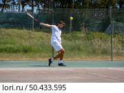 Tennis player hitting backhand at ball with racket on court. Стоковое фото, агентство Ingram Publishing / Фотобанк Лори