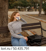 woman with medical mask sitting bench. Стоковое фото, агентство Ingram Publishing / Фотобанк Лори