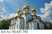 A majestic white Orthodox church with golden domes stands in a park with colorful autumn trees under a blue sky with clouds. Стоковое AI-видео, аниматор Sergey Grishin / Фотобанк Лори