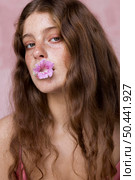 portrait freckled woman with flower her mouth. Стоковое фото, агентство Ingram Publishing / Фотобанк Лори