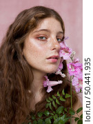 portrait mysterious freckled woman holding pink flower. Стоковое фото, агентство Ingram Publishing / Фотобанк Лори