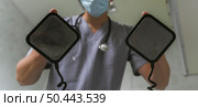 doctor with medical mask using defibrillator. Стоковое фото, агентство Ingram Publishing / Фотобанк Лори
