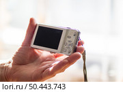 Belarus, Minsk - 09.03.2025: A person is firmly gripping a small and compact white camera in their hand. Редакционное фото, фотограф Аксенова Вера / Фотобанк Лори