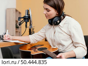 side view female musician home writing song while playing acoustic guitar. Стоковое фото, агентство Ingram Publishing / Фотобанк Лори