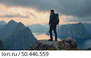 Amazing epic shot of young man hiker stand on top of mountain after long difficult hike in Lofoten Islands in Norway. Incredible summer views. Стоковое AI-видео, аниматор Sergey Grishin / Фотобанк Лори