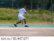 Tennis player hitting backhand at ball with racket on court. Стоковое фото, агентство Ingram Publishing / Фотобанк Лори