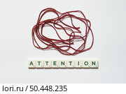 Attention word formed of scrabble blocks with tangled thread over white background. Mental health awareness.. Attention formed of scrabble blocks with tangled thread. Стоковое фото, агентство Ingram Publishing / Фотобанк Лори