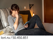 Woman on bed at phone with symptoms of depression. Стоковое фото, агентство Ingram Publishing / Фотобанк Лори
