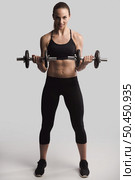 Beautiful young woman in a workout gear lifting dumbbells. Стоковое фото, агентство Ingram Publishing / Фотобанк Лори