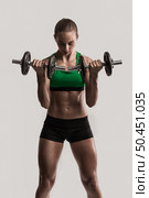 Beautiful young woman in a workout gear lifting dumbbells. Стоковое фото, агентство Ingram Publishing / Фотобанк Лори