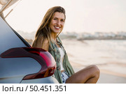 Beautiful woman sitting in the trunk of a car near a beach and smilling. Стоковое фото, агентство Ingram Publishing / Фотобанк Лори
