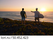Surfers watching the waves at sunset on top of a sand dune in Maceda, Ovar -  Portugal. Стоковое фото, агентство Ingram Publishing / Фотобанк Лори