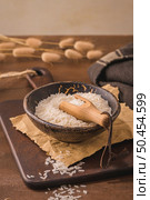 Long grain rice in ceramic bowl with wooden scoop on rustic countertop. Стоковое фото, агентство Ingram Publishing / Фотобанк Лори