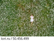 Beautiful girl lies in camomile daisy flower. View from above. Aerial photography. Стоковое фото, агентство Ingram Publishing / Фотобанк Лори