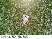 Beautiful girl lies in camomile daisy flower. View from above. Aerial photography. Стоковое фото, агентство Ingram Publishing / Фотобанк Лори